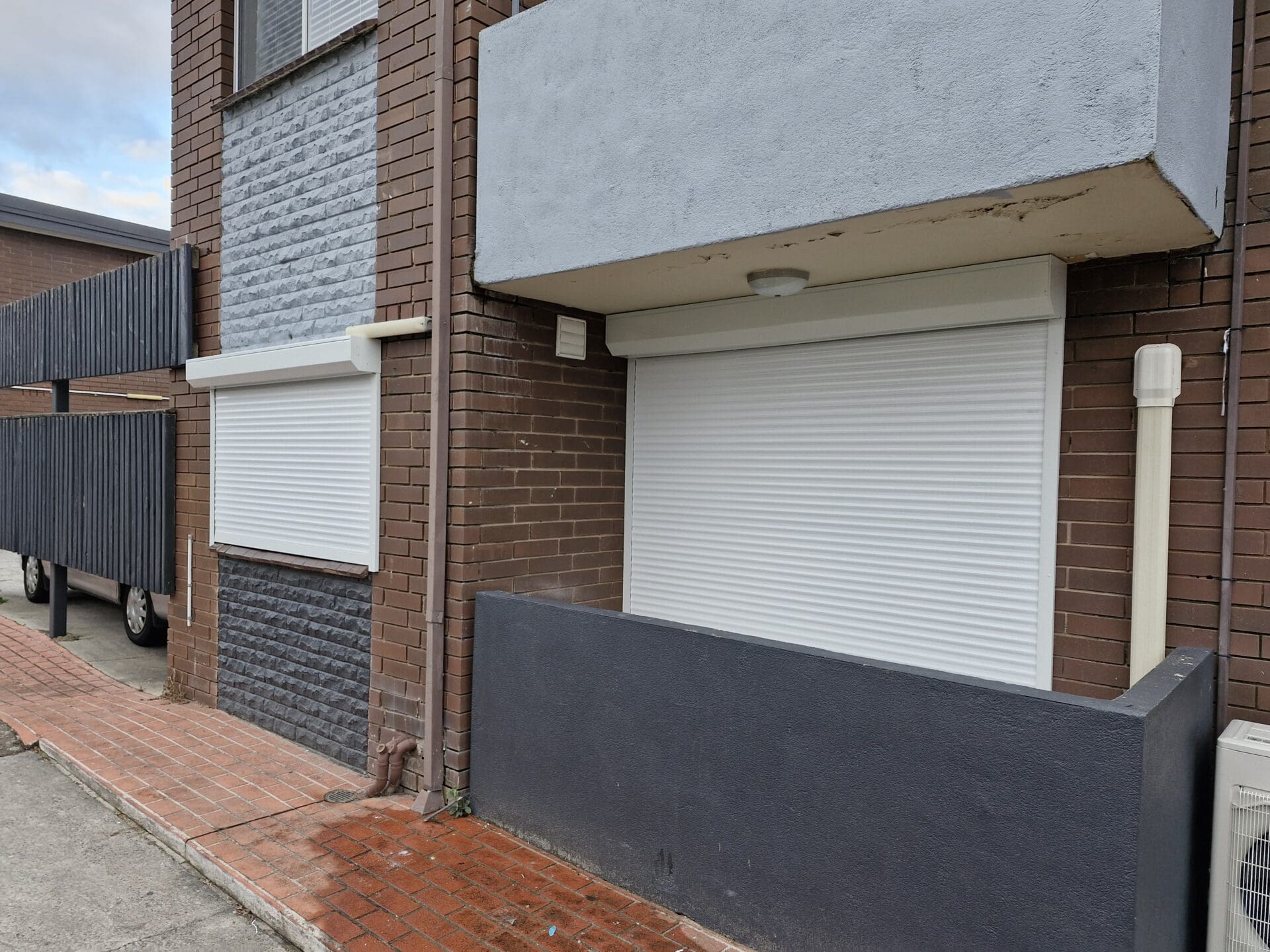 a building with a brick wall and a white shutter